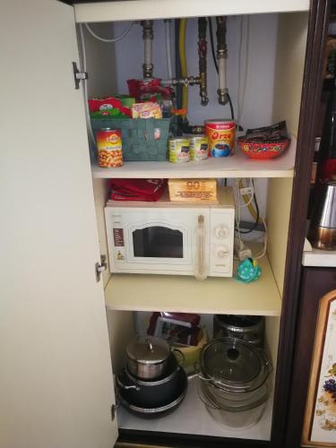 a kitchen pantry with a microwave and pots and pans at Sia & Sophie House Oradea in Sîntandrei