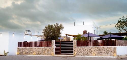 a white building with a fence and some umbrellas at PAIISE Hotels in Sant Francesc de s'Estany