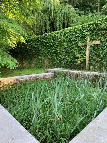 a cross on a hedge next to a garden with a cross at La Porterie de l’Abbaye de Marche les Dames in Namur