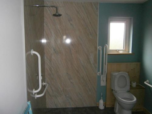 a bathroom with a toilet and a window at Otter Bunkhouse in Cairisiadar