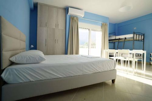 a bedroom with blue walls and a bed and a dining room at Villa Mimoza in Borsh