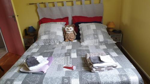 un lit avec un hibou rembourré assis au-dessus dans l'établissement VOLCANS D'AUVERGNE - PONTAUMUR, à Pontaumur