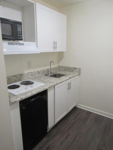 a kitchen with white cabinets and a black dishwasher at Stay Lodge Anderson in Anderson