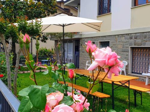 a wooden table with an umbrella and pink flowers at B&B Figura Apartments in Borgo San Lorenzo
