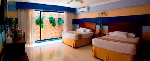 a bedroom with two beds and a large window at Hotel Plaza Colonial in Campeche