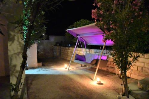a canopy bed with lights in a backyard at night at Apartments Alma in Pag
