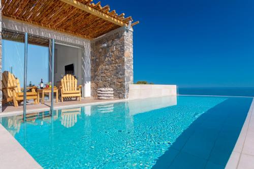 Cette villa dispose d'une piscine avec une table et des chaises. dans l'établissement Atermono Boutique Resort & Spa, à Platanias