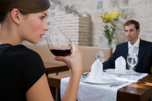 a woman sitting at a table with a glass of wine at Hotel Vestibul Palace & Villa - Small Luxury Hotels Of The World in Split