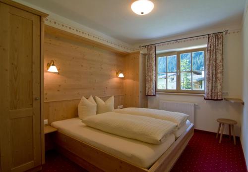 um quarto com uma cama e uma parede de madeira em Landhaus Wildes Wasser em Neustift im Stubaital