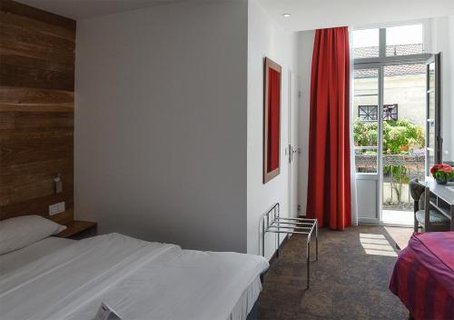 ポンにあるHotel de Bordeauxのベッドルーム1室(ベッド1台、赤いカーテン付)