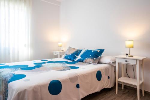 Schlafzimmer mit einem Bett mit einer blauen und weißen Bettdecke in der Unterkunft Lindo y acogedor departamento in Torre del Mar
