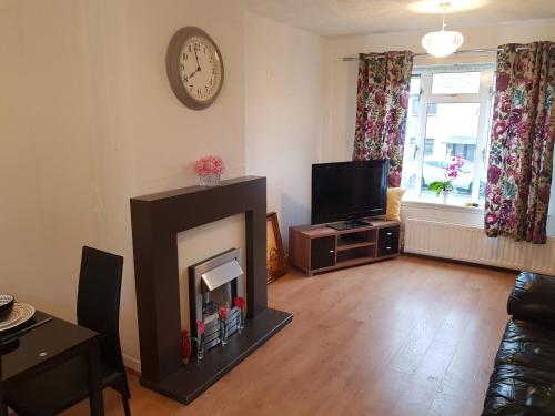 a living room with a fireplace and a tv at Cosy house near Edinburgh and St Andrew's in Kirkcaldy