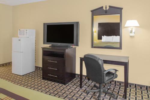 a room with a television and a chair in a hotel room at Days Inn by Wyndham Andalusia in Andalusia