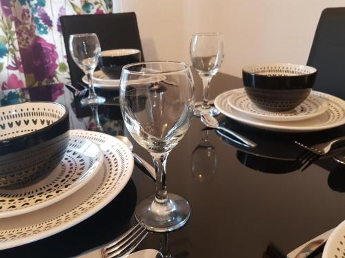 a table with plates and wine glasses on it at Cosy house near Edinburgh and St Andrew's in Kirkcaldy
