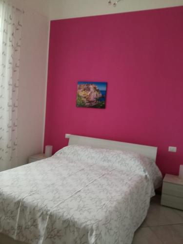 a bedroom with a white bed and a pink wall at Dalla Maestra Lucia in Procida