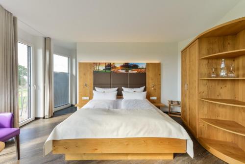 a bedroom with a large bed and a purple chair at Hotel & Golfrestaurant Gut Wissmannshof in Staufenberg