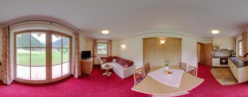 a living room with a large window and a table at Landhaus Wildes Wasser in Neustift im Stubaital