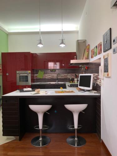 アヴォラにある''A casa di Lele''のキッチン(赤いキャビネット、ピンクのスツール付きカウンター付)