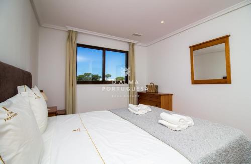 een slaapkamer met een bed met witte lakens en een raam bij D'Alma Falésia Beach Apartment - By Dalma Portuguesa in Albufeira