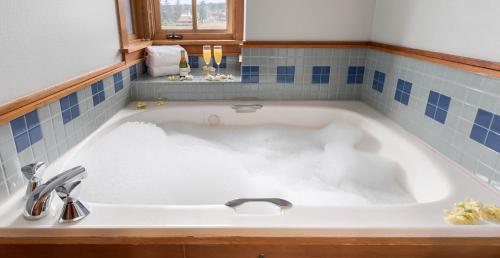 a white bath tub in a bathroom with blue tiles at La Conner Channel Lodge in La Conner
