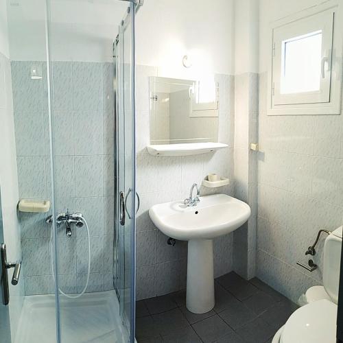 a white bathroom with a sink and a shower at Sunset Apartments in Perdika
