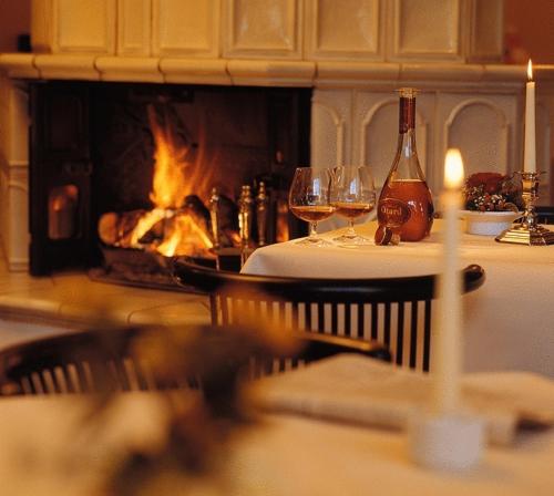 a table with glasses of wine and a fireplace at Hotel Harheimer Hof in Frankfurt/Main