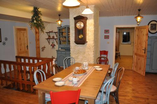 a dining room with a wooden table and a clock at Horská chalupa U Hančilů in Pec pod Sněžkou