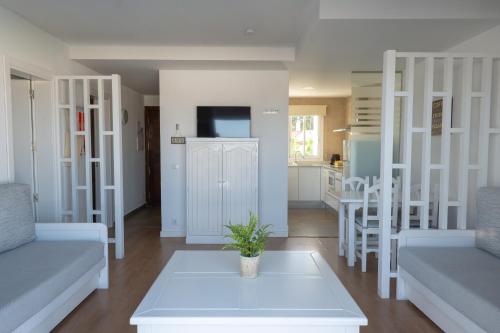 a living room with white furniture and a table at Naranjos Resort Menorca in S'Algar
