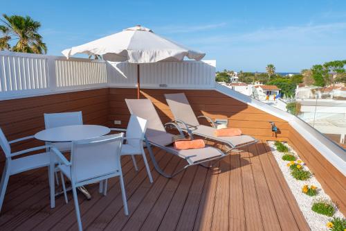 a deck with a table and chairs and an umbrella at Naranjos Resort Menorca in S'Algar