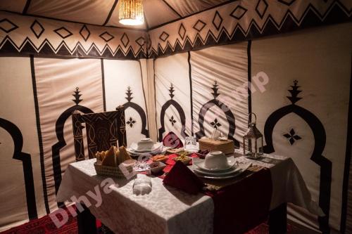 a dining room with a table with a white table cloth at Dihya desert camp in Merzouga