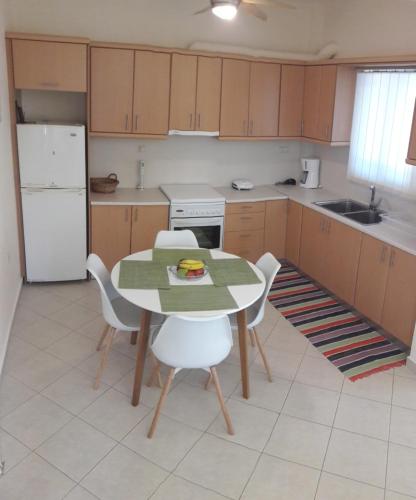 cocina con mesa, sillas y nevera blanca en STERNES house, en Agios Leon