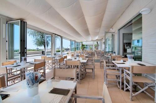 ein Restaurant mit Tischen, Stühlen und Fenstern in der Unterkunft Hotel Levante in Caorle
