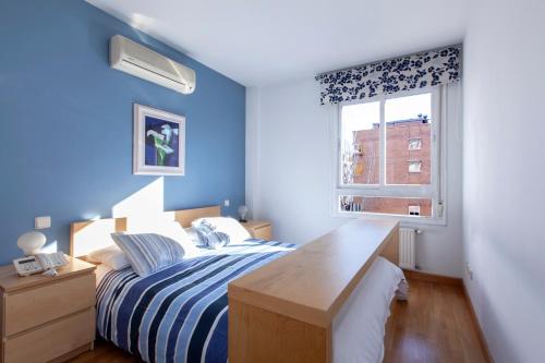 Dormitorio azul con cama y ventana en RASTRO, en Madrid
