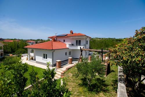 Casa blanca con techo rojo en Apartmani Villa Zora, en Lopar