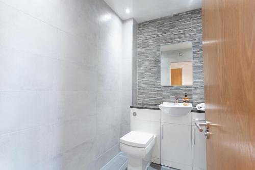 a white bathroom with a toilet and a sink at CITY CENTRE APARTMENT with Free Secure Underground Parking in Glasgow