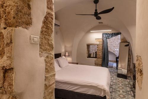 a bedroom with a white bed and a stone wall at Alma in ‘Akko