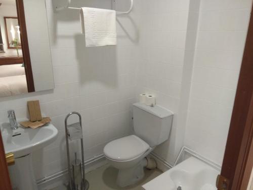 a white bathroom with a toilet and a sink at La mesa del cocinero in Lugo