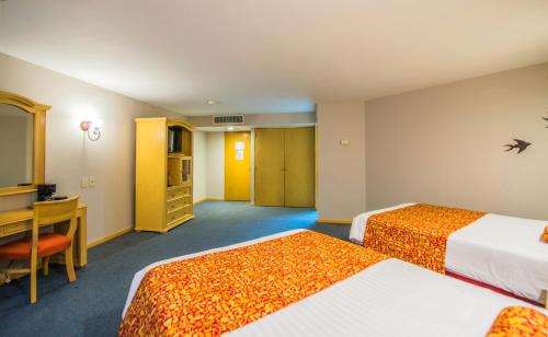 a hotel room with two beds and a desk at Aranzazu Plaza Kristal Aguascalientes in Aguascalientes