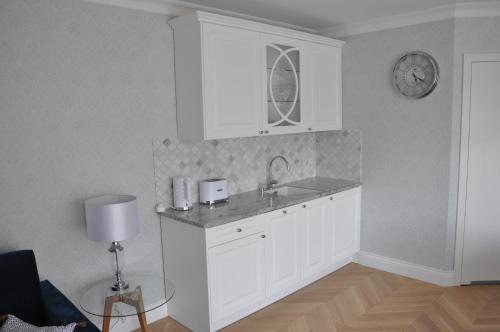 een witte keuken met een wastafel en een klok aan de muur bij Apartament Bello Mechelinki in Mechelinki