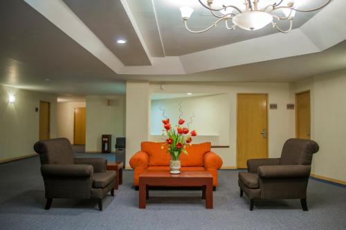 a waiting room with chairs and a orange couch and flowers at Aranzazu Plaza Kristal Aguascalientes in Aguascalientes