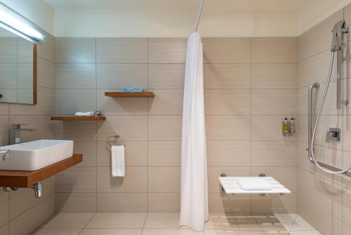 Taipa Beach Resort في Taipa: حمام مع دش ومغسلة ومرحاض