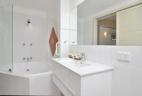 a white bathroom with a sink and a mirror at Le Cher Du Monde Adults Only in Port Douglas