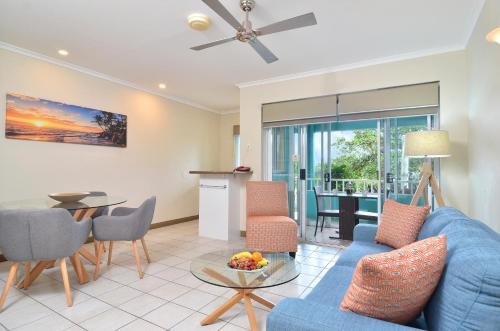 a living room with a blue couch and a table at Le Cher Du Monde Adults Only in Port Douglas