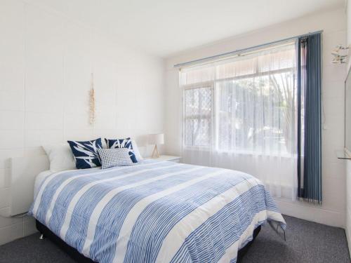 a white bedroom with a bed and a window at Forster Holiday Lodge 4 - Central location! in Forster