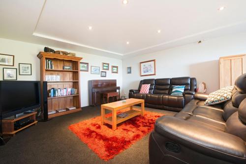 a living room with a leather couch and a television at Selah Retreat in Nelson
