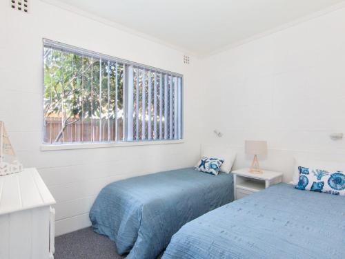 two beds in a white room with a window at Forster Holiday Lodge 4 - Central location! in Forster