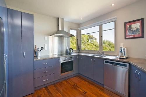a kitchen with blue cabinets and a large window at Selah Retreat in Nelson