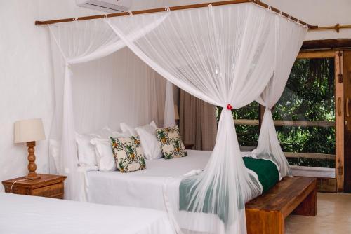 a bedroom with a canopy bed with white curtains at Hotel Boutique Bahia Bonita in Trancoso