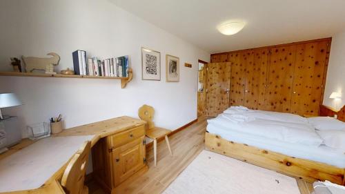1 dormitorio con cama de madera y escritorio en Flurina 42, en Silvaplana