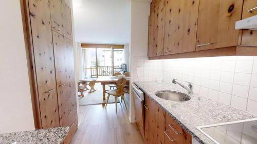 uma cozinha com armários de madeira, um lavatório e uma mesa em Flurina 42 em Silvaplana